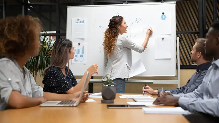 A woman writing on a dry erase board, "Custom FQHC Consulting | Tailored Strategy & High-Impact Collaboration"
